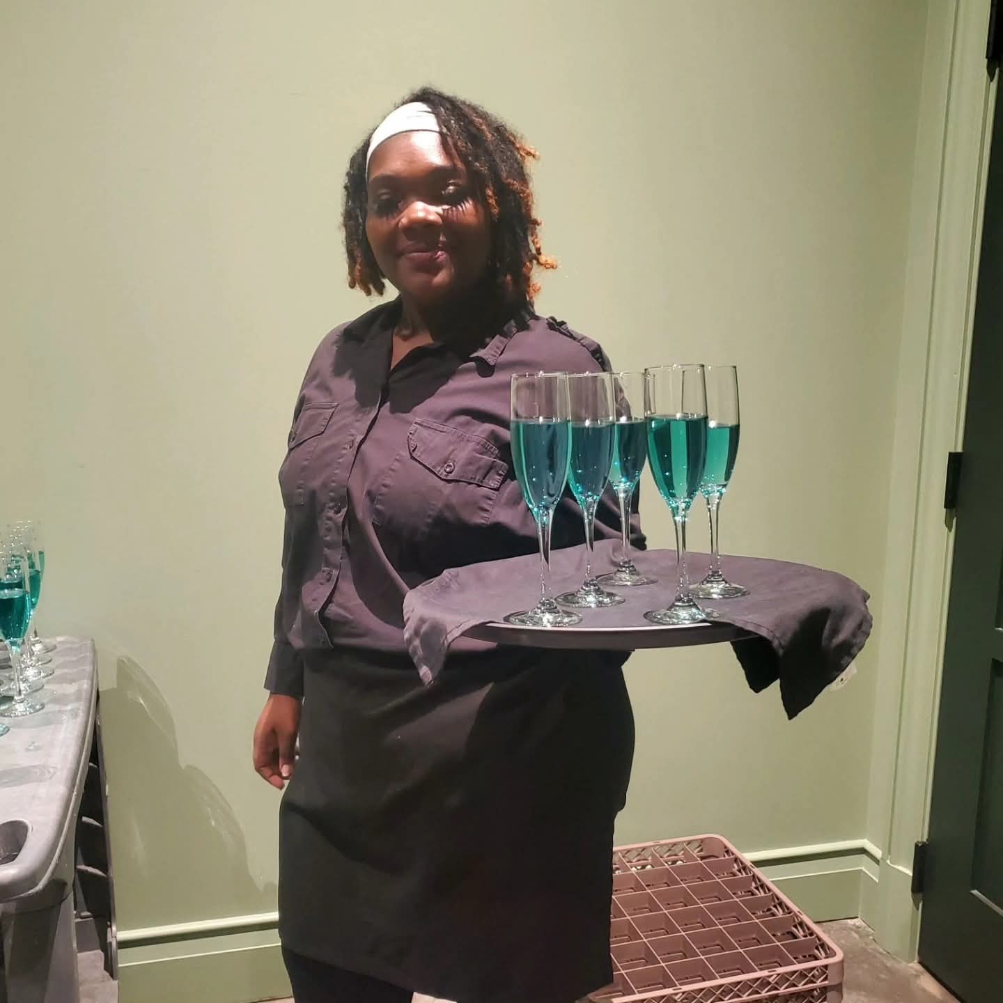 A 2 Girlz and A Tray server presenting a tray of sparkling cocktails